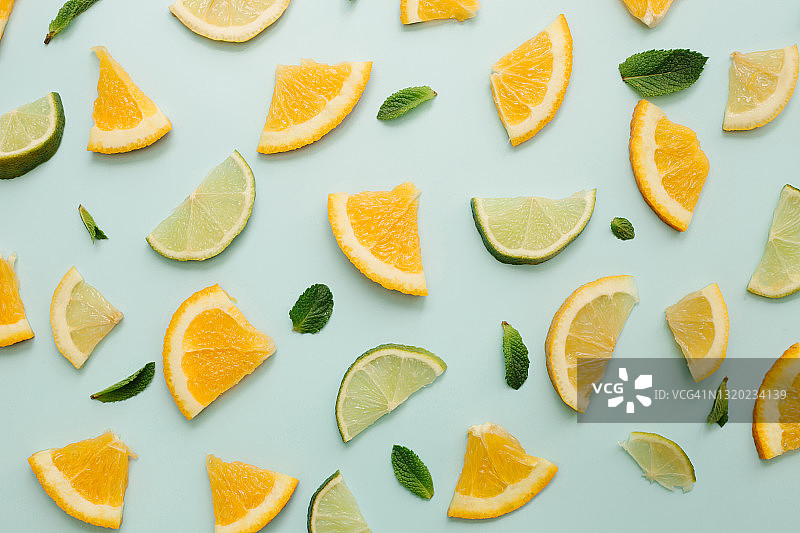 薄荷、柠檬片、酸橙和橙子水果在蓝色背景上的抽象背景，带水滴图片素材