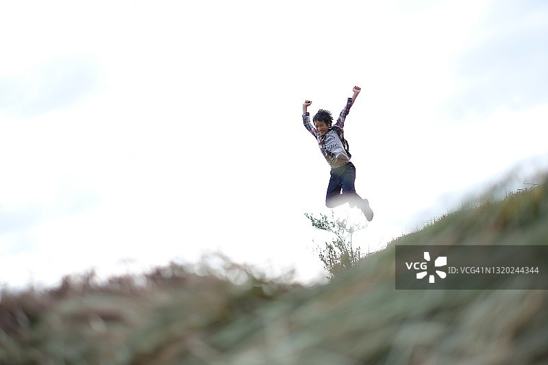 男孩在稻田间的小路上跳跃图片素材