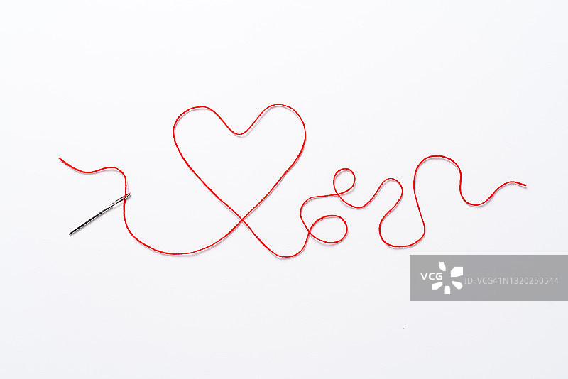 穿过缝纫针的红色心形线爱情概念图片素材