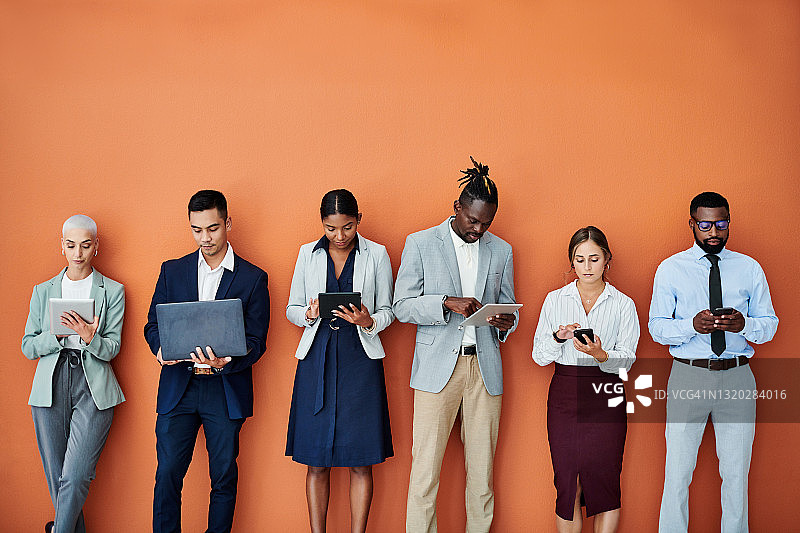 一群使用数字设备的商人，橙色背景图片素材