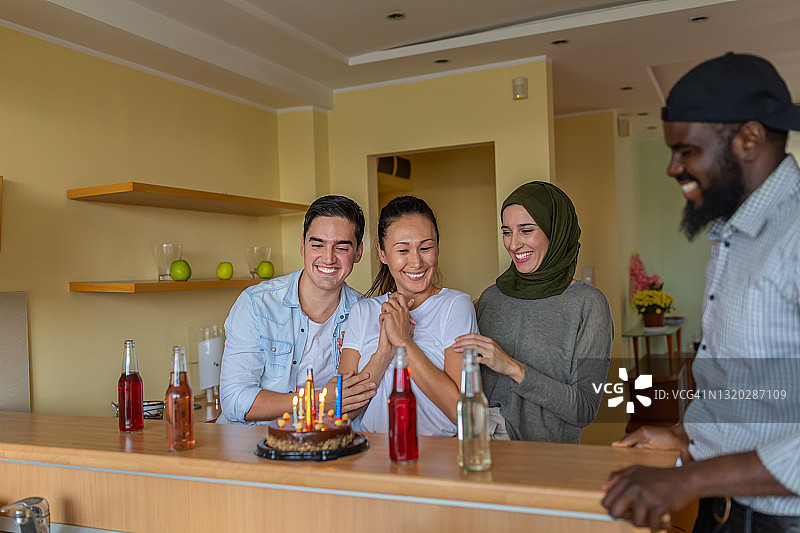 快乐的多元民族朋友在现代公寓放松身心，享受生日派对图片素材