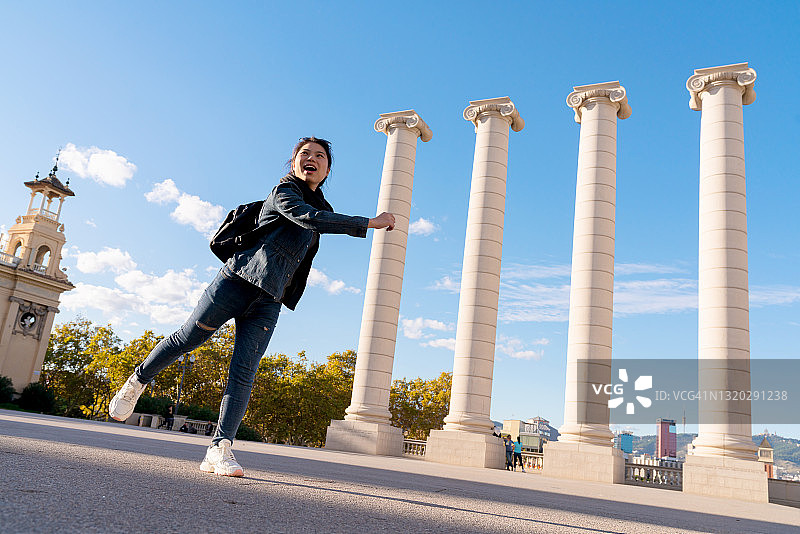亚洲女性游客在西班牙巴塞罗那的科隆广场步行和拍照图片素材