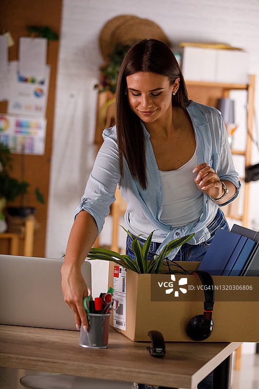 微笑的女商人正在新办公室的办公桌旁整理物品图片素材