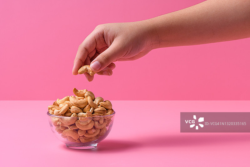 孩子的手从碗里拿起腰果的特写图片素材