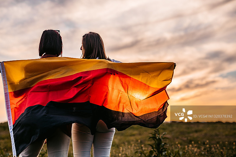 两个女人在草地上用德国国旗遮盖身体图片素材