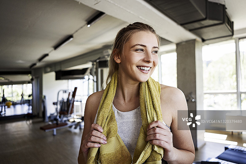 在健身房拿着毛巾的微笑健身女孩图片素材