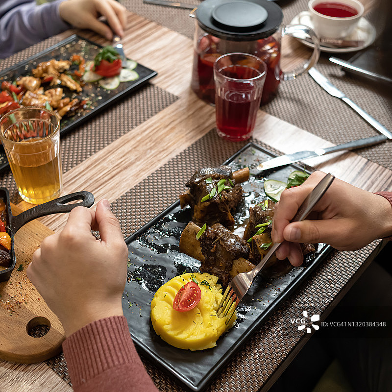 朋友在餐厅共享午餐或晚餐，品尝美味佳肴图片素材