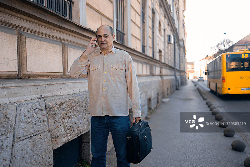 成年男人走向办公楼并用手机交谈图片素材