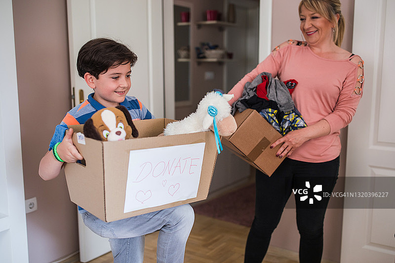 快乐的母亲和儿子拿着装满捐赠物品的盒子图片素材