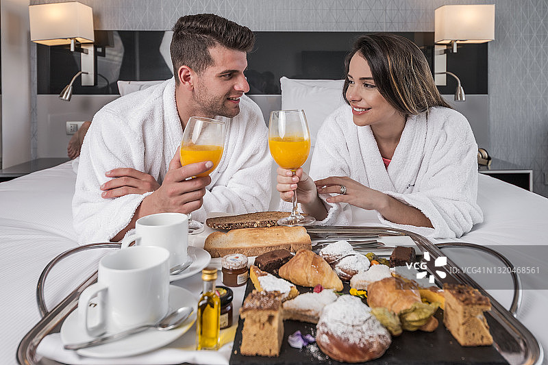 在酒店卧室里享用早餐的幸福夫妇图片素材