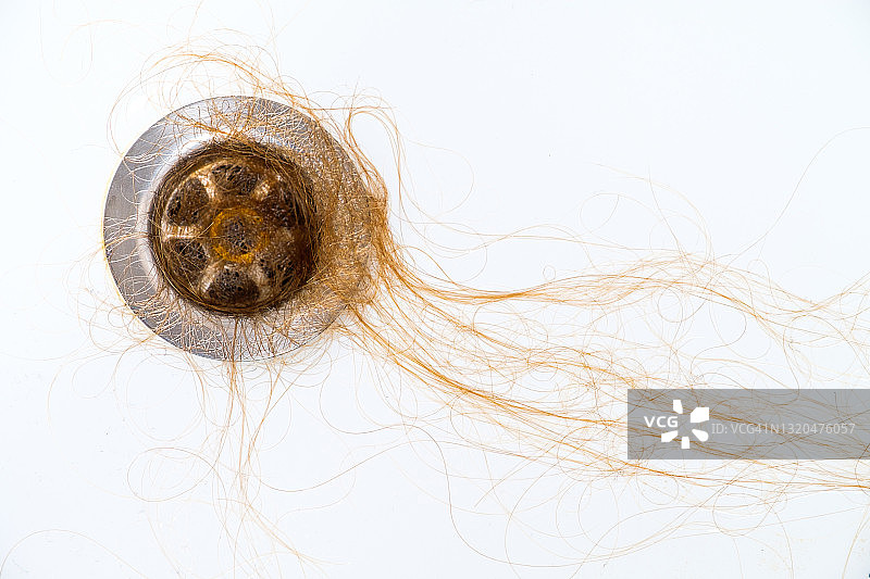 洗发或淋浴后浴室水槽排水口中的散落头发。头部健康问题，因压力和抑郁引起的身体机能不足，癌症化疗和放疗的后果的概念图片素材