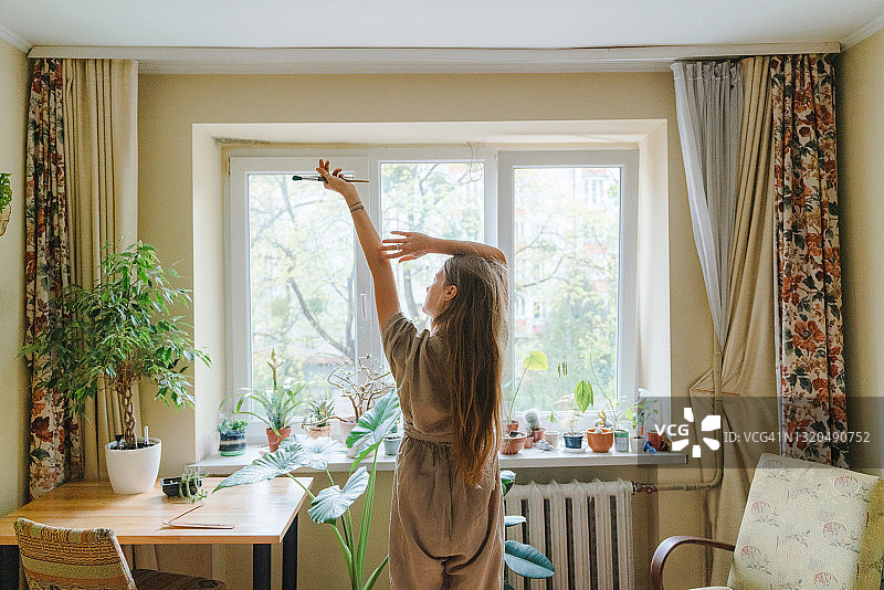 在家中窗边伸展身体的女画家图片素材