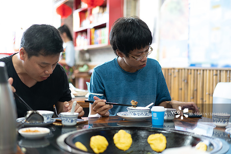 两位亚洲男子边吃边交流图片素材