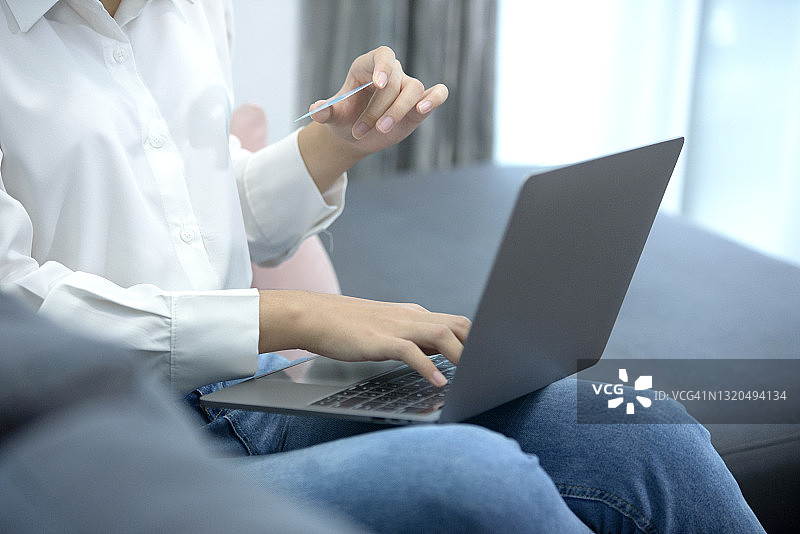 年轻女人手持身份证用笔记本电脑输入个人资料图片素材