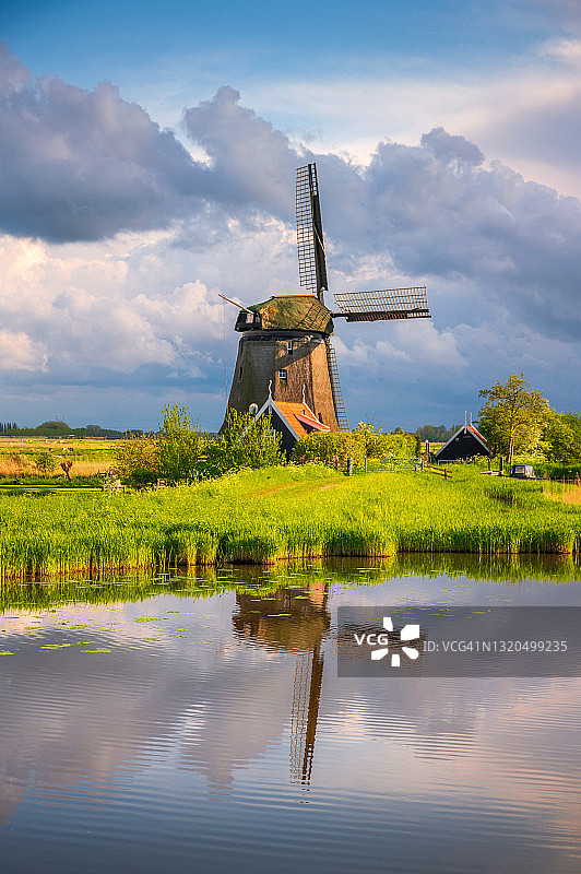 平静的河流中倒映着传统的荷兰风车和云彩图片素材