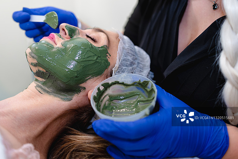 在诊所使用绿色海藻进行面部补水护理图片素材