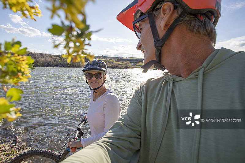 山地自行车情侣沿河边骑行图片素材