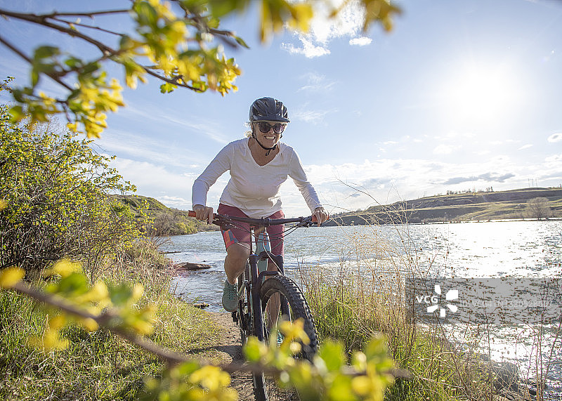 骑山地自行车的女人沿着河边骑行图片素材