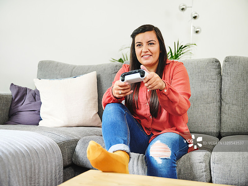 女子在家中沙发上放松玩游戏的场景图片素材