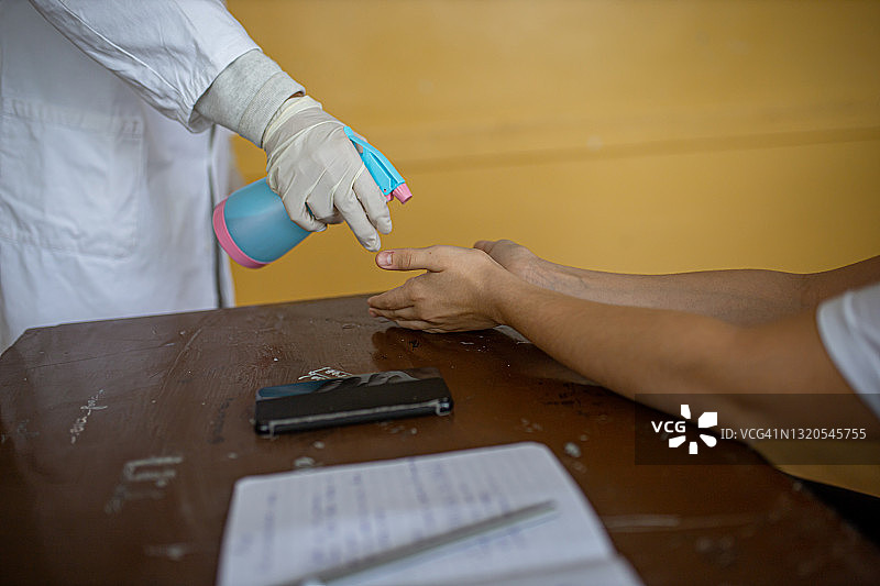 教师在教室里为学生的手消毒图片素材