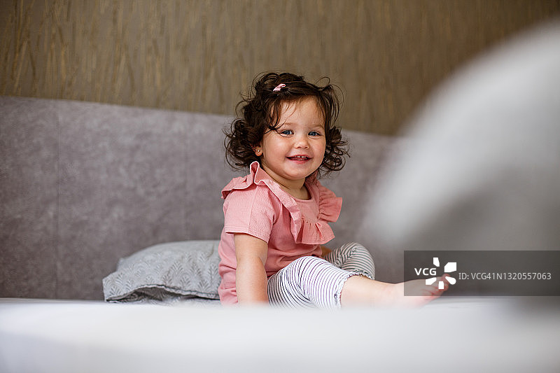 微笑的小女孩坐在卧室的床上图片素材