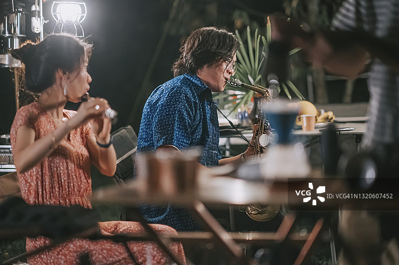 中国年轻夫妇在花园派对上演奏萨克斯和长笛图片素材
