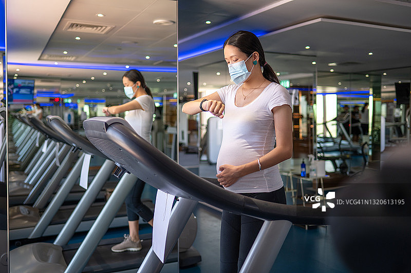 孕妇在健身房的跑步机上行走，以保持怀孕期间的健康和活力图片素材