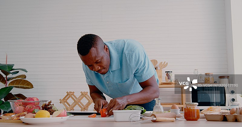 在厨房切菜的年轻非洲裔男人图片素材