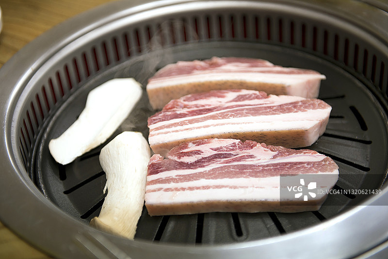 传统韩式烤肉：烤架上的五花肉和蘑菇图片素材