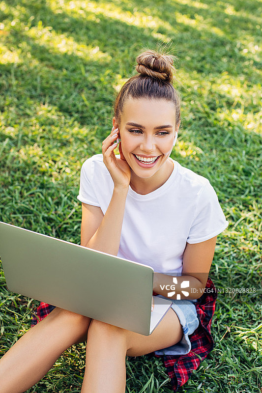 女人坐在公园里使用笔记本图片素材