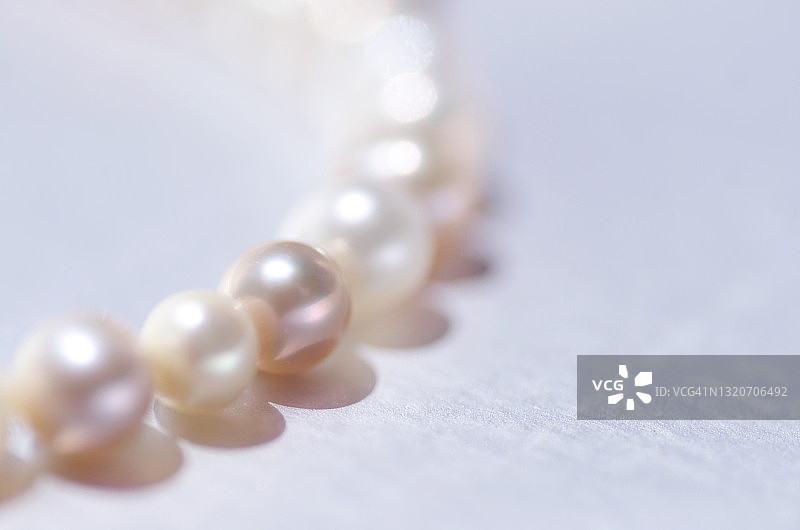银色背景上的粉色珍珠项链特写，留有文案空间图片素材