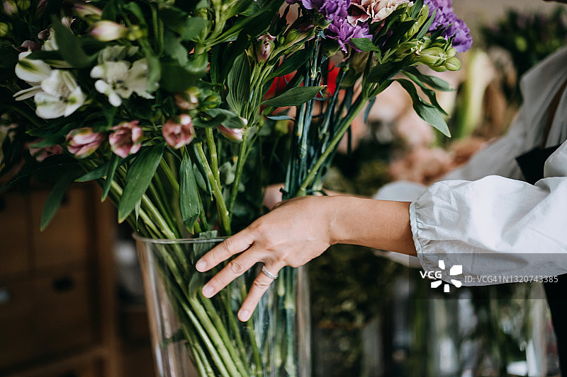 亚洲女花店主手捧鲜花花瓶特写：小企业主在工作场所精心照料花卉，享受与花为伴的乐趣，小企业概念图片素材