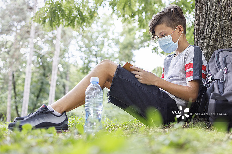 在公园里戴着口罩做作业的年轻男人图片素材