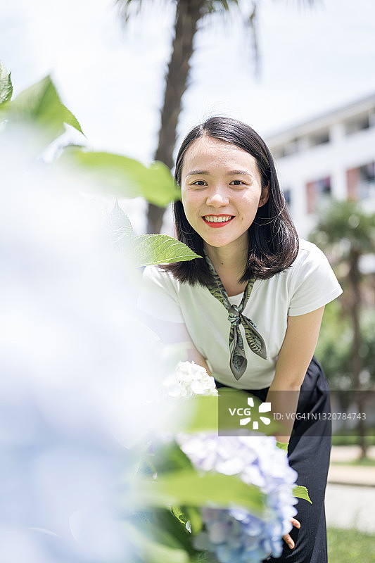 蹲在花丛中的亚洲女人。图片素材