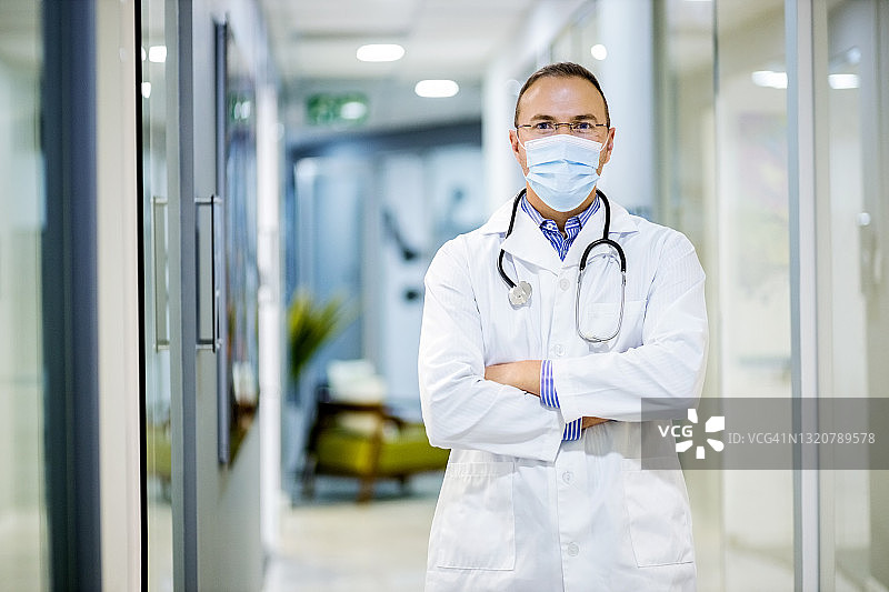 戴着口罩自信的医生站在走廊上的画像图片素材