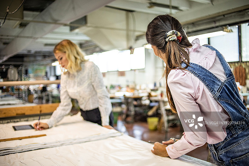 在时装工厂创造新产品的两位年轻女人，专注于时尚图片素材