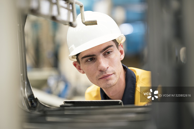 质检员随机检查生产线上托盘上的成品机器零件底盘，质量保证概念图片素材