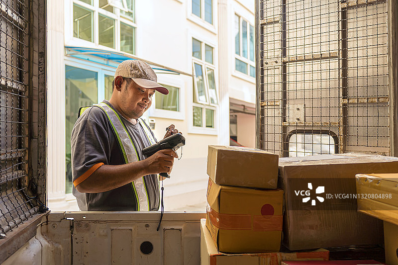 快递员扫描纸箱上的条形码，卸货准备派送图片素材