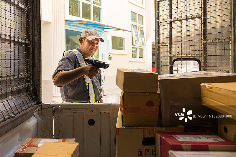 快递员扫描纸箱上的条形码，卸货准备派送图片素材