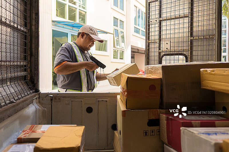 快递员扫描纸箱上的条形码，卸货准备派送图片素材
