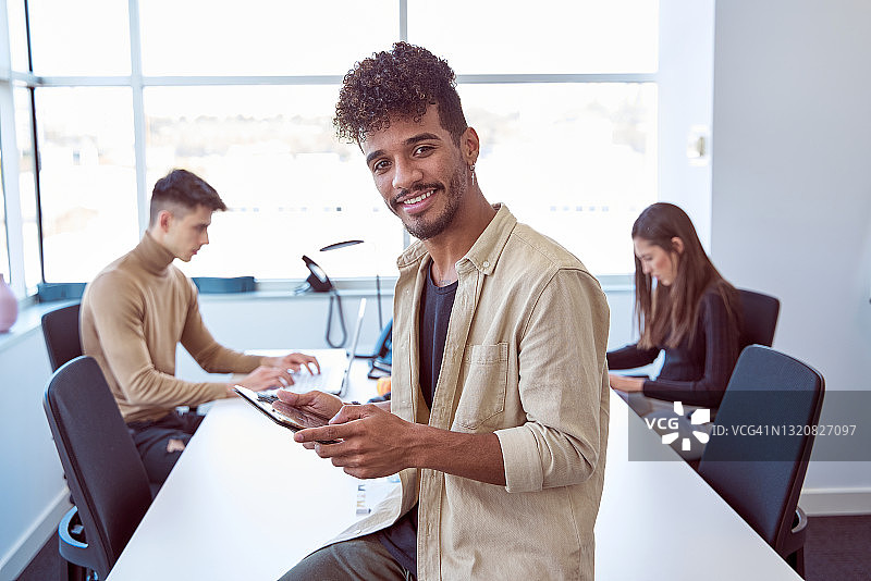 与白人同事在办公室办公桌旁工作的拉丁裔商人使用平板电脑图片素材