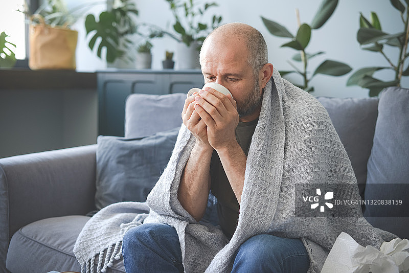 生病的男人坐在房间的沙发上图片素材
