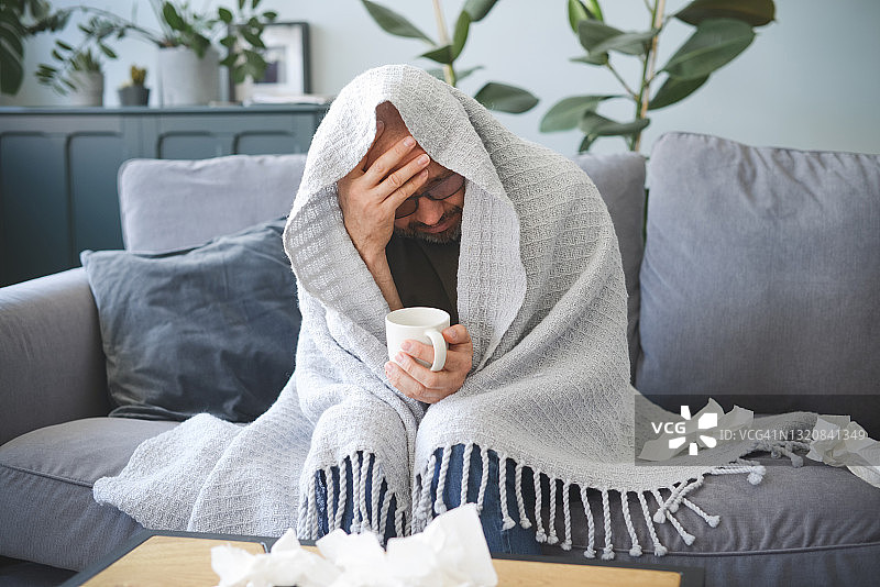 生病的男人坐在房间的沙发上图片素材