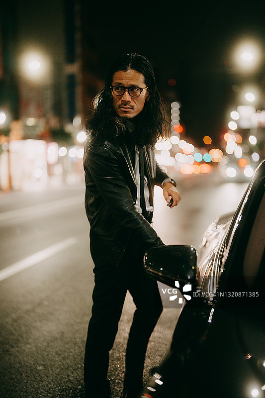 男人站在东京的夜间街道汽车旁图片素材