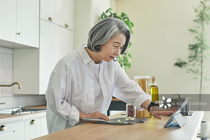 正在用菜谱烹饪的老妇人图片素材