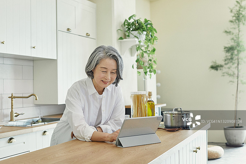老妇人通过电子设备阅读食谱图片素材