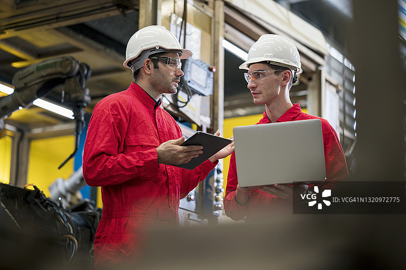 工业工程师讨论控制汽车零件焊接自动化机器人的工作标准流程图片素材