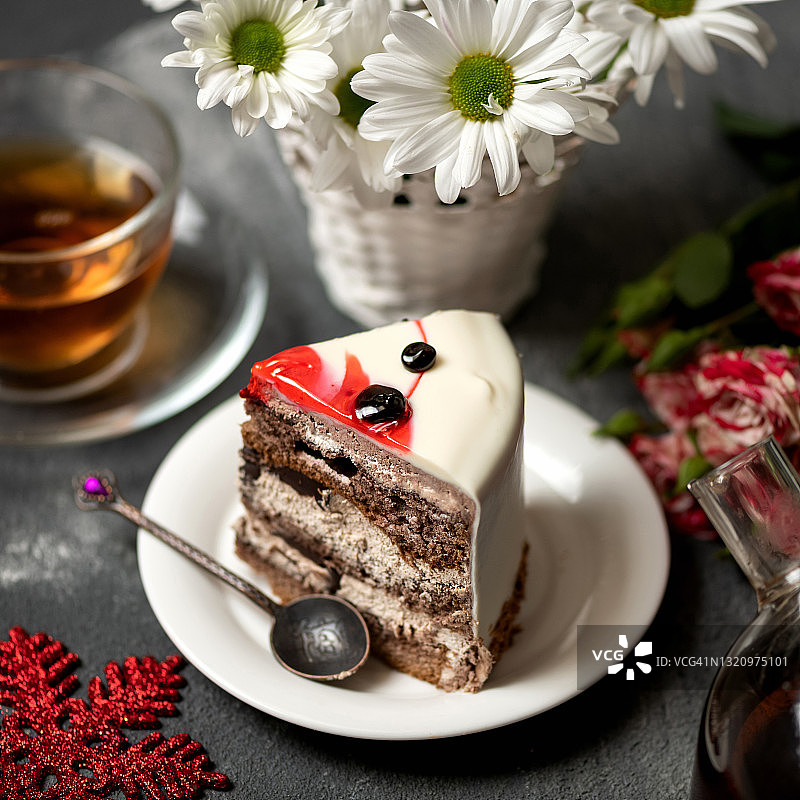 新年甜点和一束鲜花。在模糊的背景上放着美味的蛋糕和白色菊花的托盘。空白的圣诞贺卡。近距离拍摄。软焦点图片素材