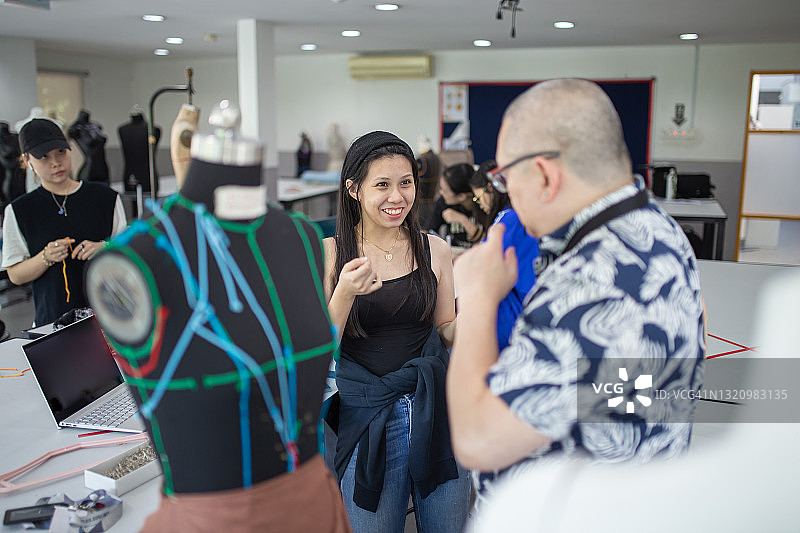 时装讲师与学生在课堂上讨论时装设计图片素材