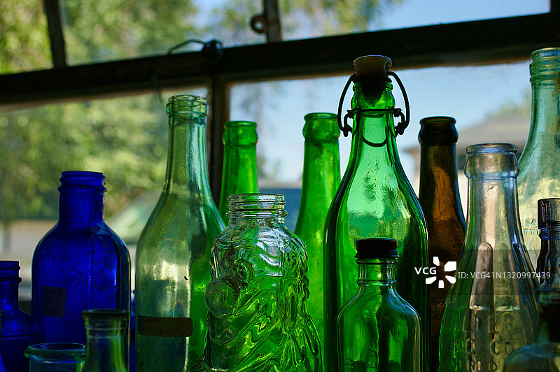 窗前透明的绿色、蓝色和棕色古董瓶照片图片素材